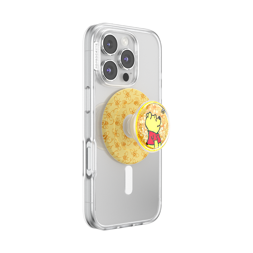 A clear protective phone case on a smartphone, featuring a round yellow Pop-Sockets grip with a Winnie the Pooh bear illustration.