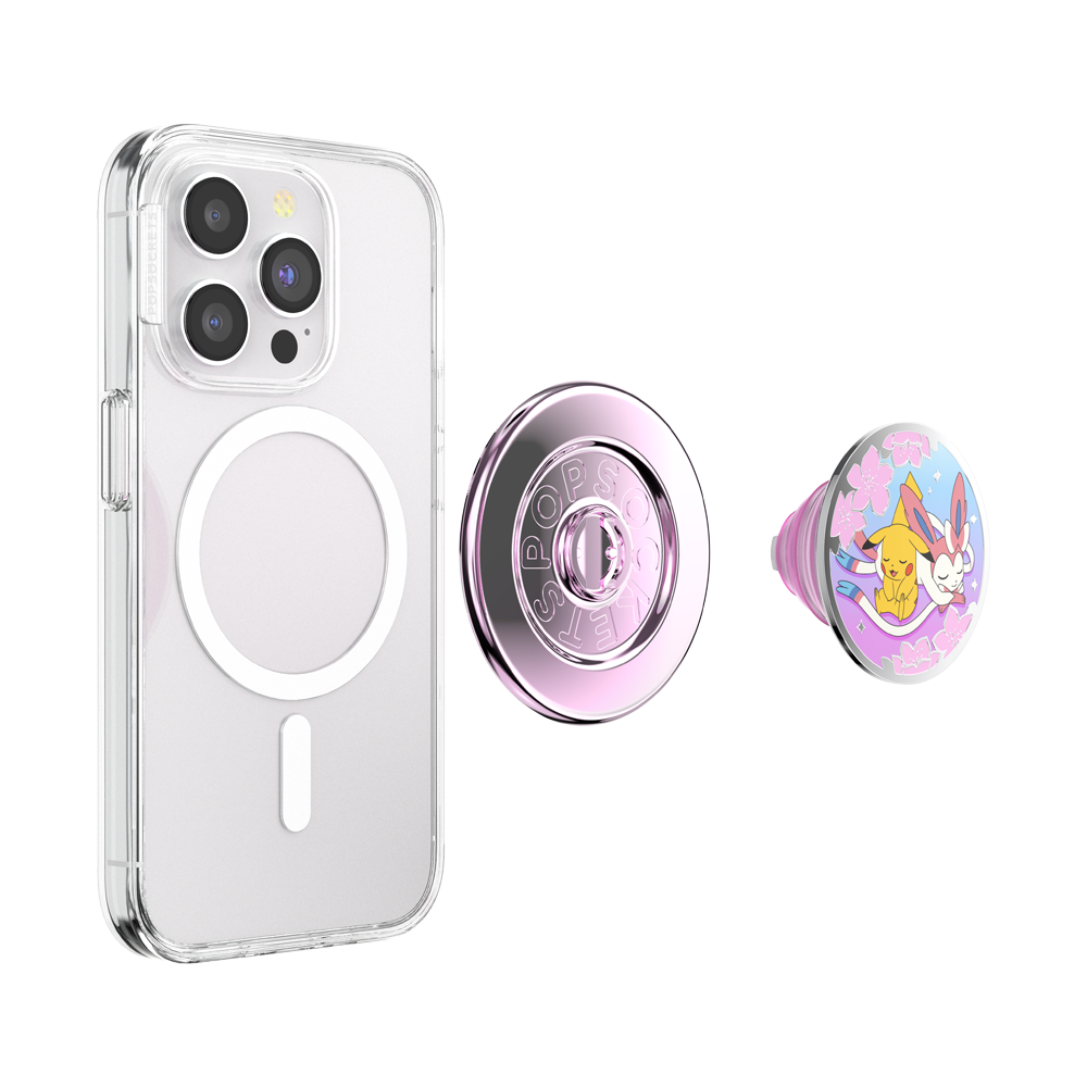 A clear MagSafe-compatible phone case shown on a smartphone, with two detachable circular pop sockets displayed beside it: one metallic pink and one pink with a colorful cartoon character design.