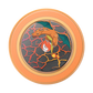 A circular Pokémon Charizard collectible coin or medallion featuring Charizard on a cracked volcanic background, surrounded by an orange metallic border on a white background.