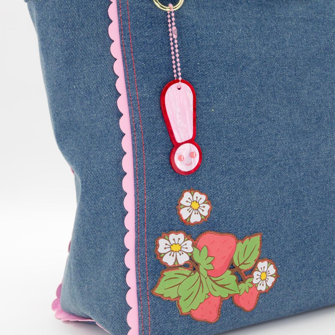 Close-up of Strawberry Shortcake smiling on a denim tote bag with red accents