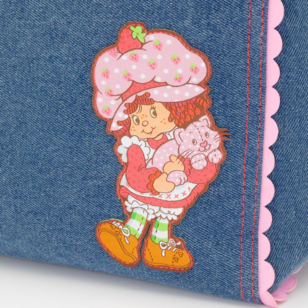 Flat lay of Whatever Makes You Happy Strawberry Shortcake denim tote against a white background