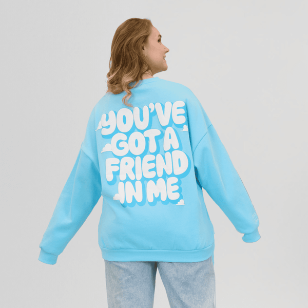 Person wearing a light blue sweatshirt with text on the back against a plain background