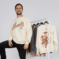 Man wearing a 'Howdy' sweater standing next to a rack of sweaters with cartoon designs.