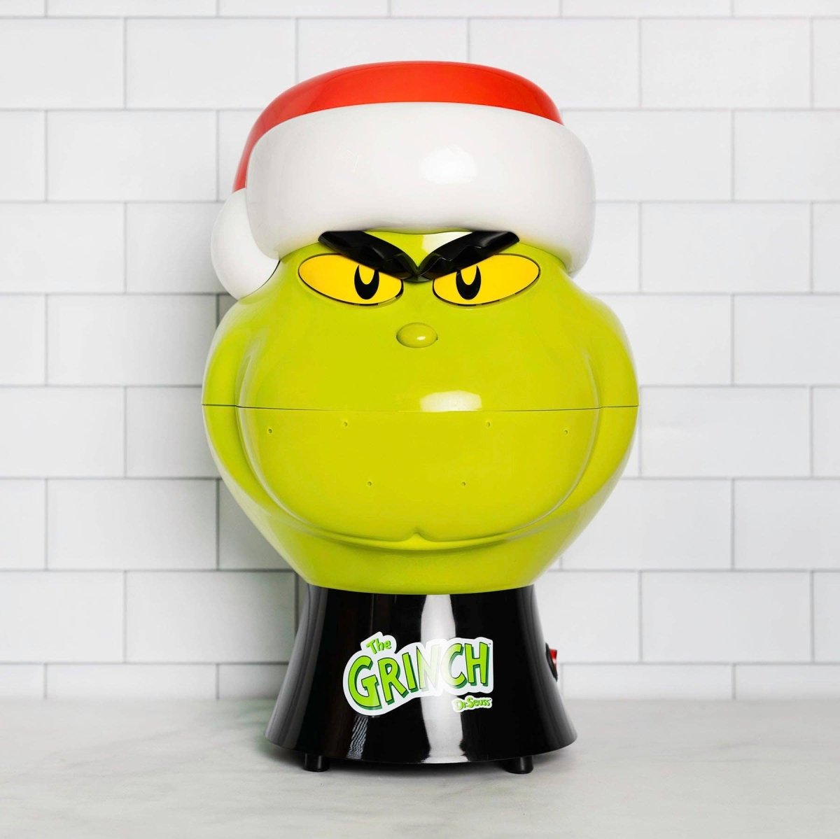 Grinch-themed gumball machine with a white tiled background