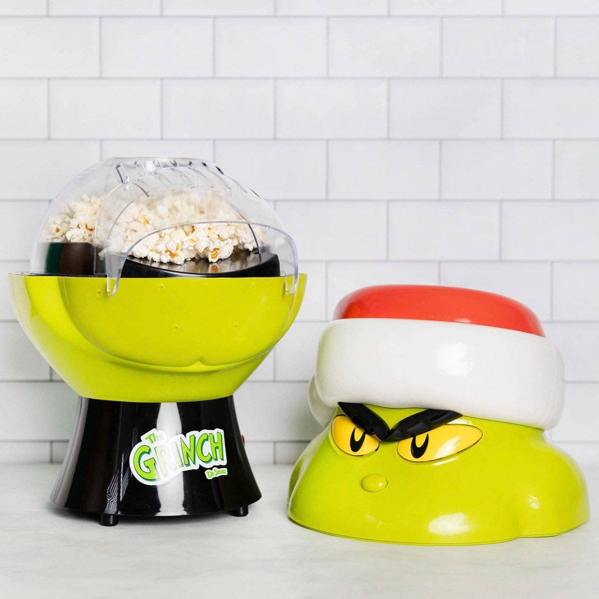 Popcorn maker with 'Grinch' design on a white tiled background