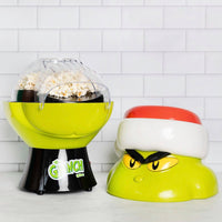Popcorn maker with 'Grinch' design on a white tiled background