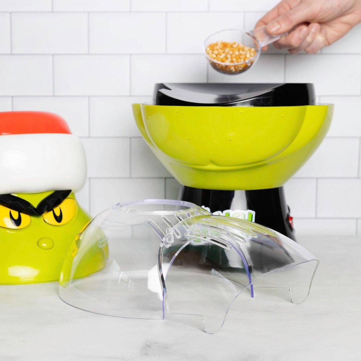 Colorful popcorn poppers on a kitchen counter with a person adding popcorn kernels.