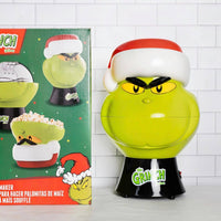 Grinch-themed popcorn maker with packaging on a tiled wall background