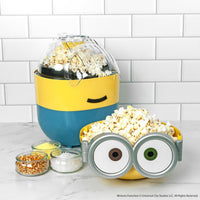 Minion-themed popcorn maker with popped popcorn on a white tiled background