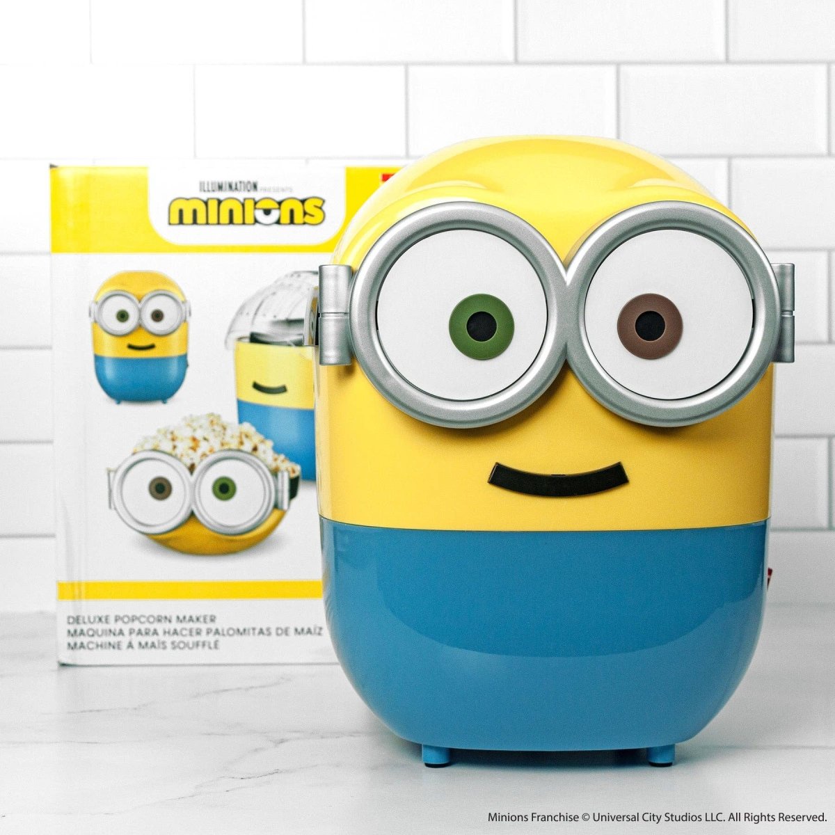 Minion-themed popcorn maker with packaging on a white tiled background