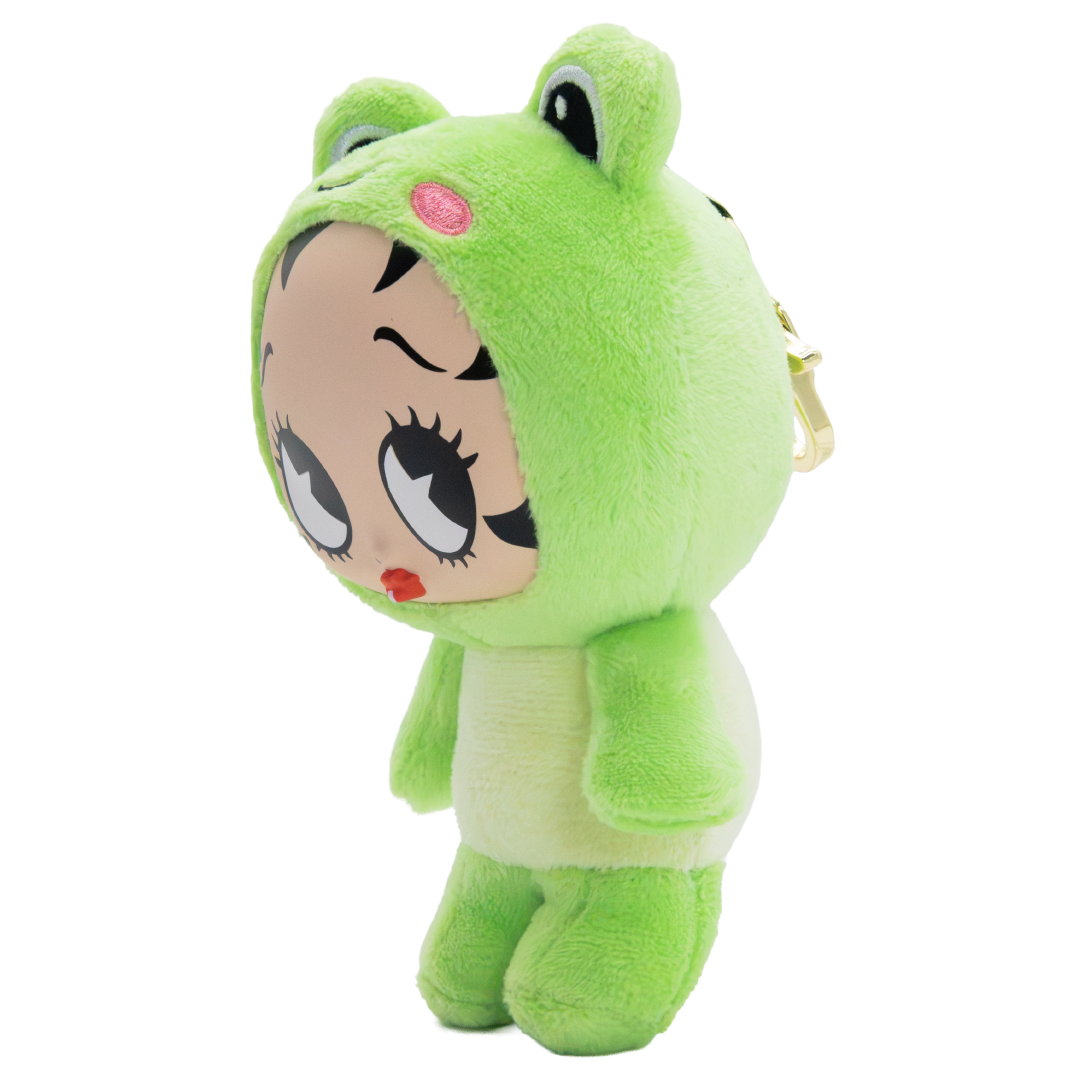 A plush toy shaped like a frog wearing a Betty Rubble-style hooded outfit, shown on a plain white background. The plush has a bright green hood and body, a pale cream face and lower body, large black-and-white cartoon eyes, a small pink oval on the hood, and a small gold keychain ring on the side.