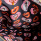A close-up of a black fabric printed with pink hearts, red lips, and Betty Boop character illustrations.