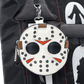A round white faux-leather bag charm designed like a hockey mask, featuring black polka dots, black eye holes, red triangular mouth details, and brown leather accents, hanging from a silver clasp on a black backpack.