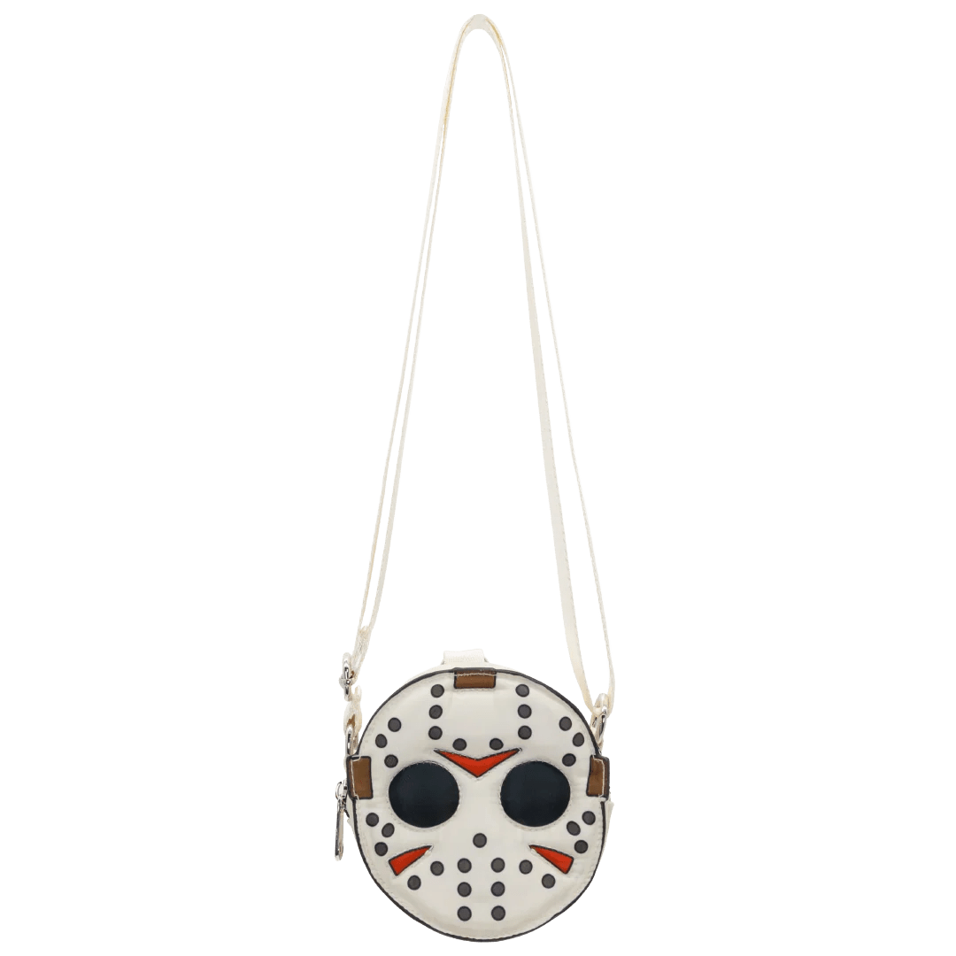A circular crossbody bag designed to look like a hockey mask, featuring a white base with black studs, black eyes, red accents, and a long white shoulder strap, shown against a plain white background.