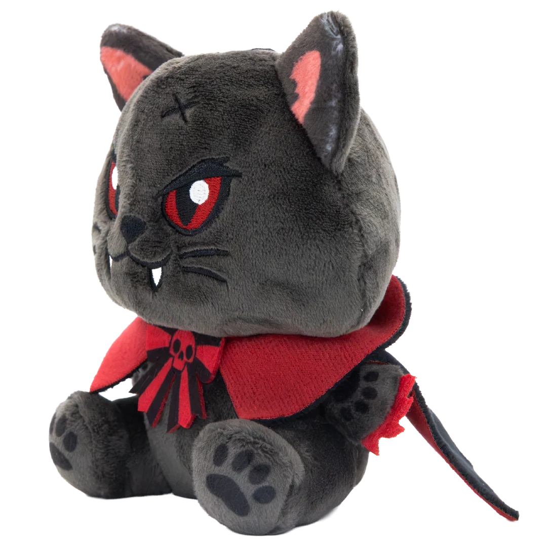 A plush toy of a dark gray cat dressed as a vampire, featuring red eyes, a red cape with a black collar, and small white fangs, set against a plain white background.