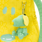 Green dog-shaped keychain attached to a yellow textured bag