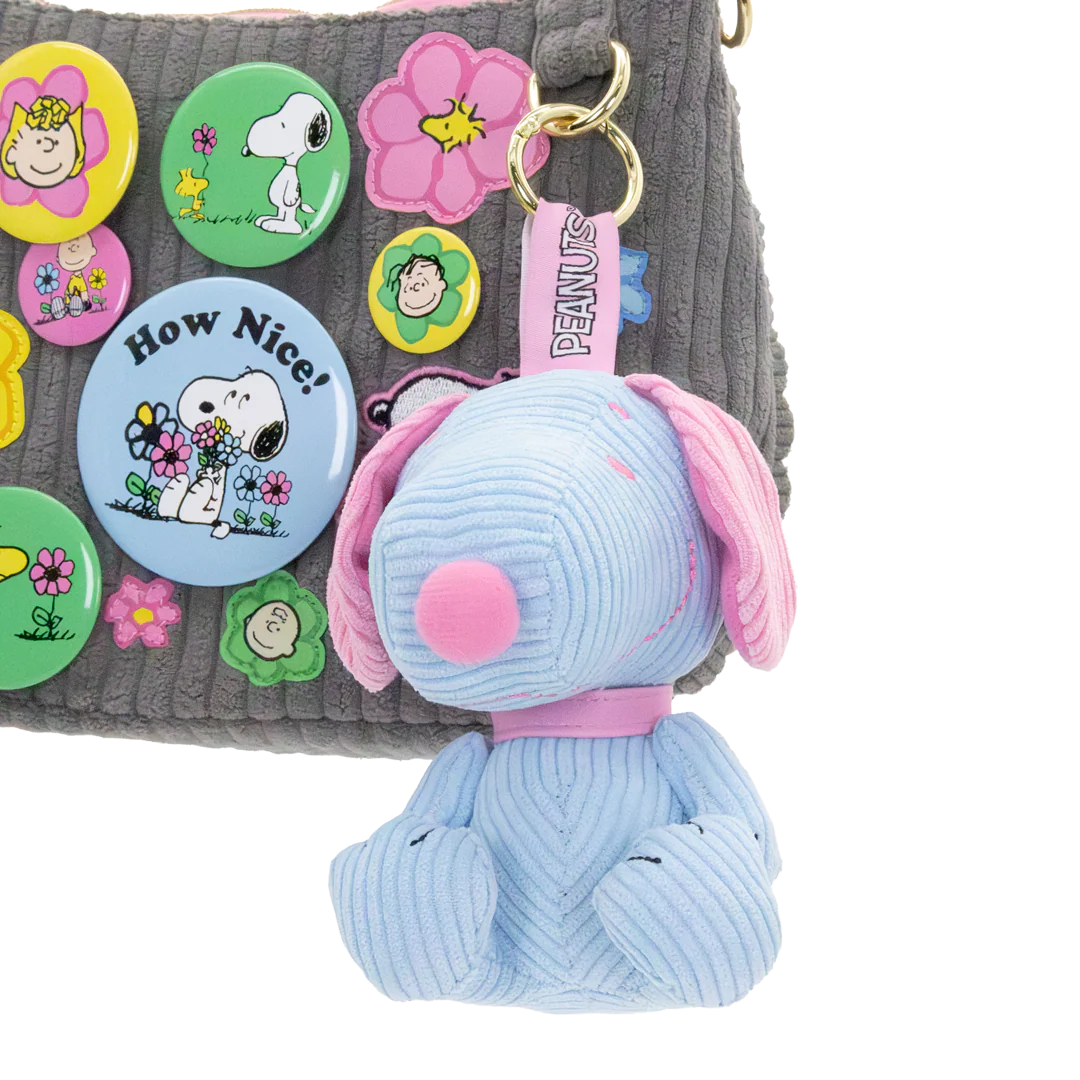 Blue dog-shaped keychain with pink collar on a gray surface with colorful buttons.