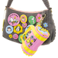 Gray handbag with colorful buttons and a pink rain boot keychain on a white background