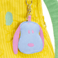 Blue and pink plush keychain attached to a yellow textured bag