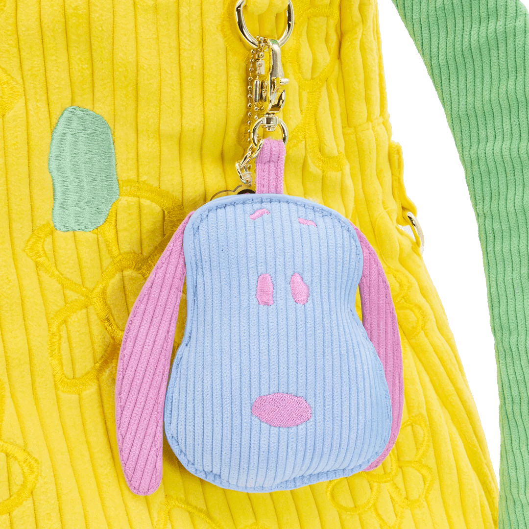 Blue and pink plush keychain attached to a yellow textured bag