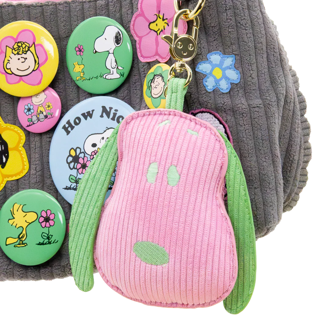 Collection of colorful cartoon buttons and a pink and green character keychain on a textured surface.