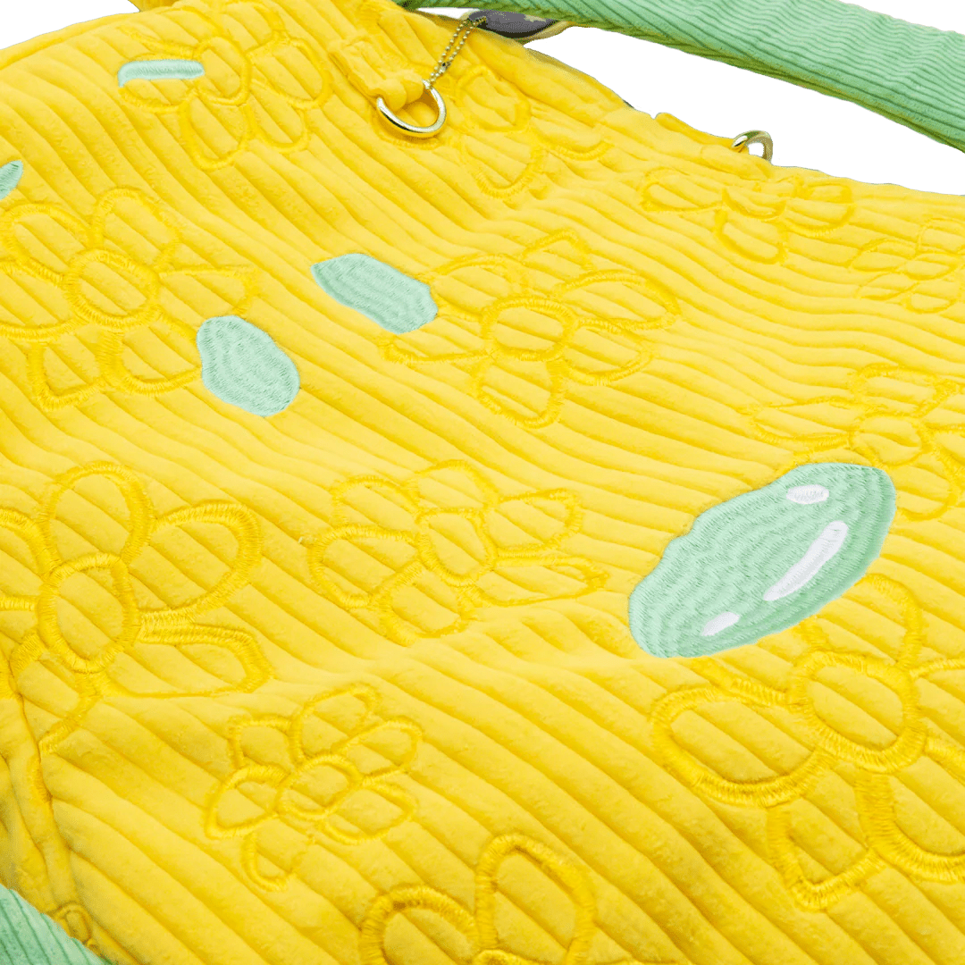 Yellow textured bag with green accents on a white background