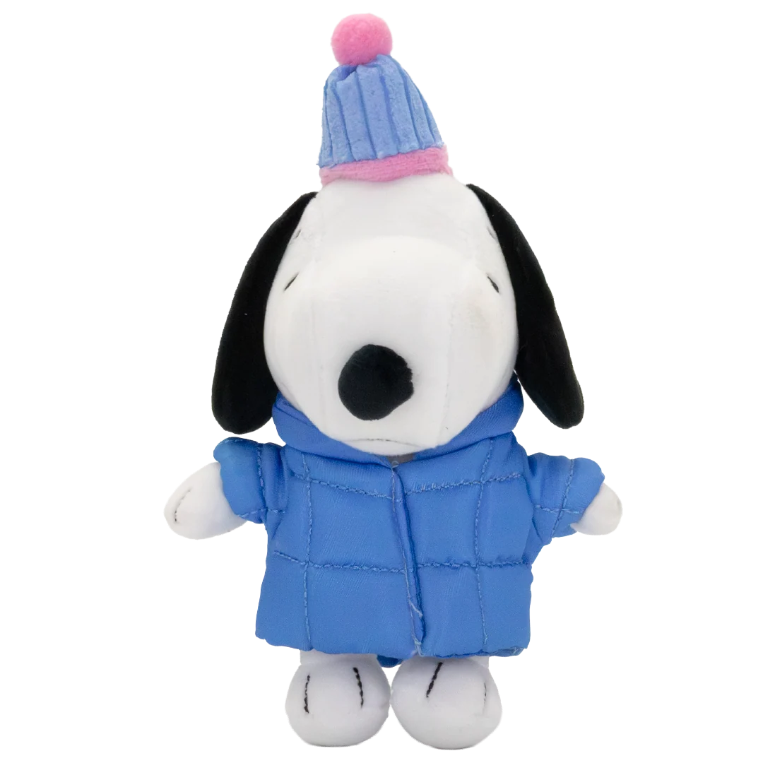 A plush toy of Snoopy wearing a blue quilted winter jacket and a blue-and-pink striped knit hat with a pink pom-pom, set against a plain white background.