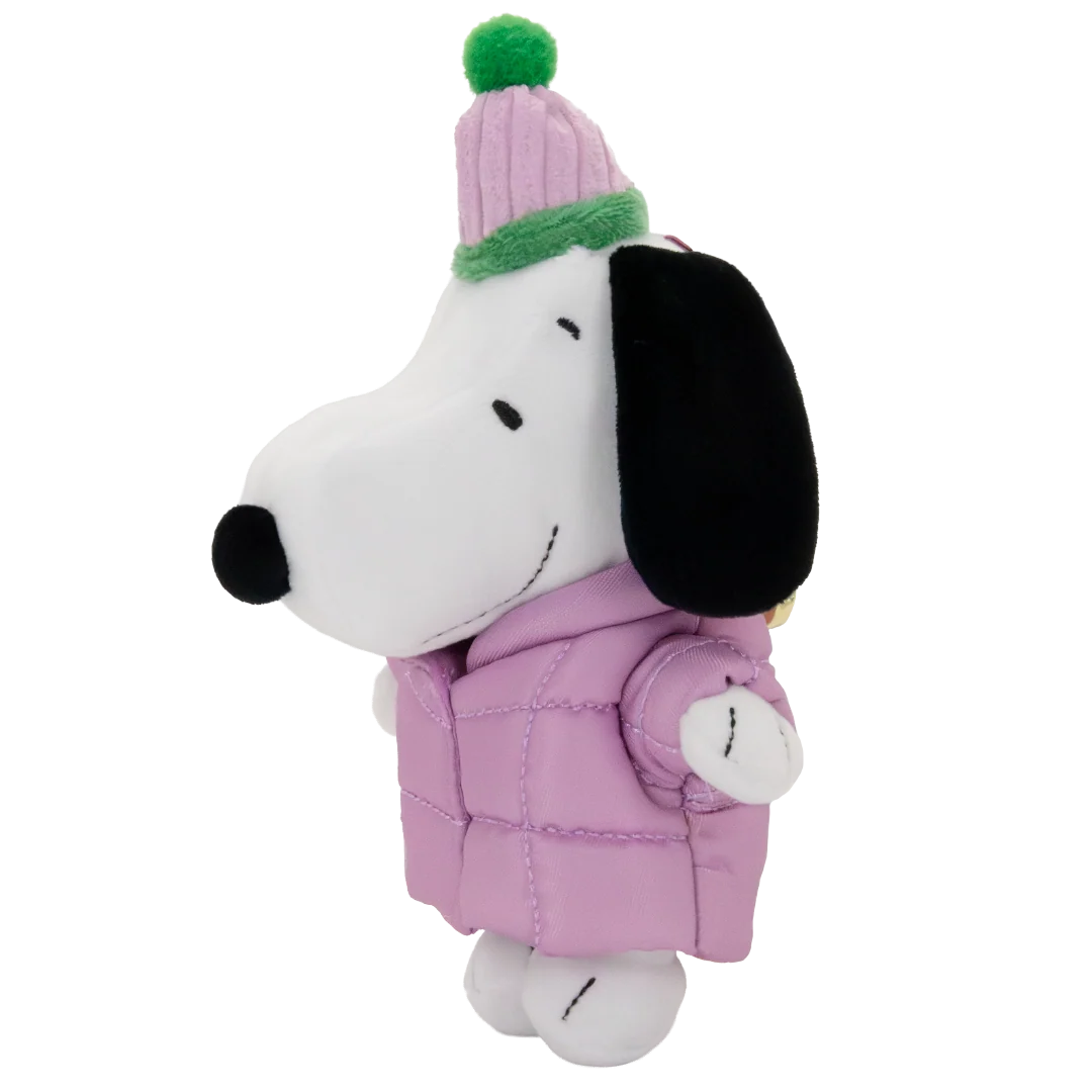 A plush toy of Snoopy wearing a pink puffer jacket and a pink knit beanie with a green pom-pom, set against a plain white background.