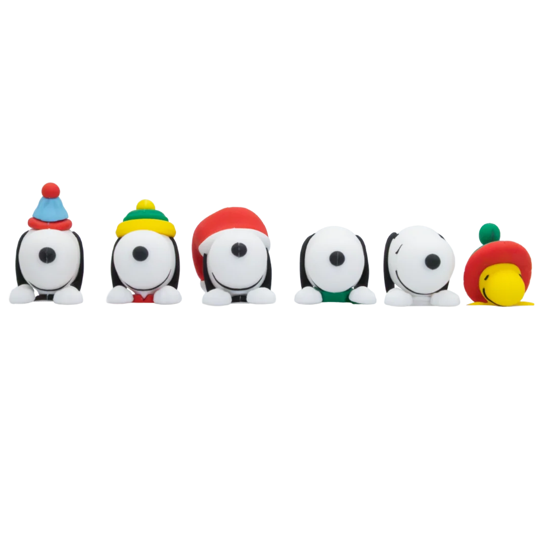 Six small Snoopy figurines lined up on a plain white background, each wearing a different colorful winter hat or scarf.