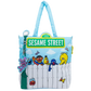 A light blue and white Sesame Street tote bag featuring characters including Big Bird, Oscar the Grouch, Tweety, and Elmo under a green 'Sesame Street' street sign, with a green street lamp charm attached.
