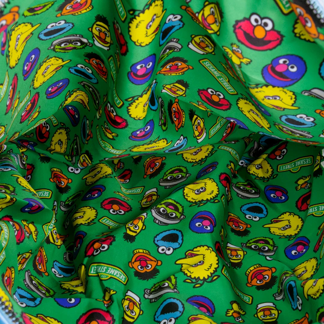 A close-up of a green fabric with an all-over print of Sesame Street character faces, including Elmo, Cookie Monster, Big Bird, and Oscar the Grouch. The fabric is draped to show its texture and pattern.