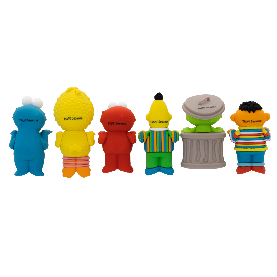 Six Sesame Street character-shaped sponge toys lined up from left to right: Cookie Monster, Big Bird, Elmo, Tony the Tiger, the Drummer, and Abby Cadabby, shown against a plain white background.