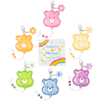 Set of colorful Care Bear keychains with a transparent packaging card featuring rainbow designs.