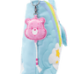 Pink bear keychain attached to a blue plush bag with rainbow and cloud design.