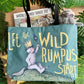 Tote bag with 'Let the Wild Rumpus Start' text and illustrations, surrounded by leaves.