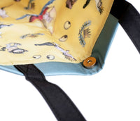 Close-up of a yellow cushion with cartoon characters and black straps on a white background