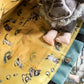 Plush donkey toy peeking out from a yellow fabric pocket with animal prints.