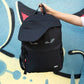 Black backpack with a face design held by a hand against a colorful background
