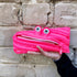 Pink zipper pouch with eyes held against a stone wall