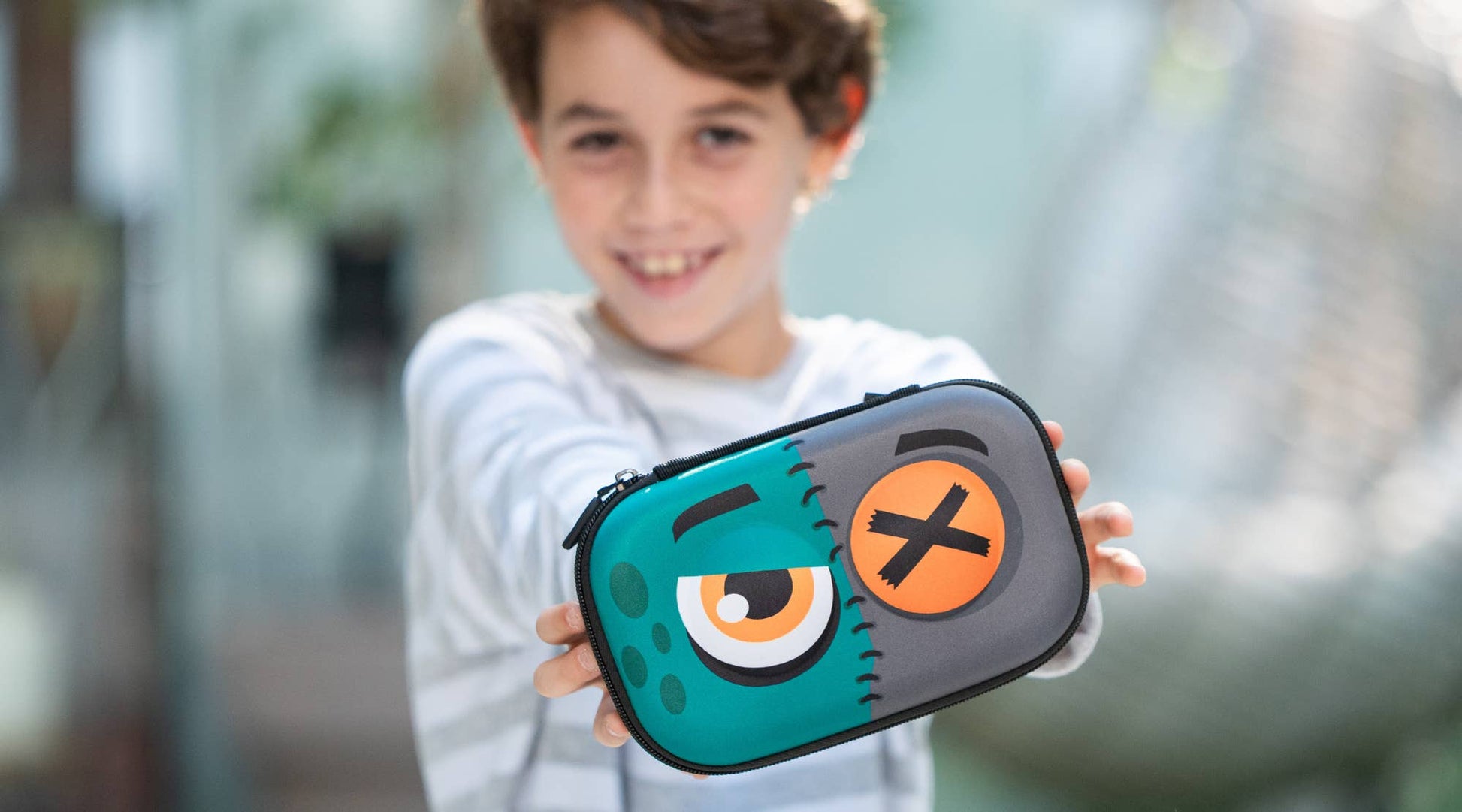 Child holding a colorful case with a cartoon character design outdoors.