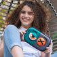 Person holding a green and black case with cartoonish design, sitting on a swing.