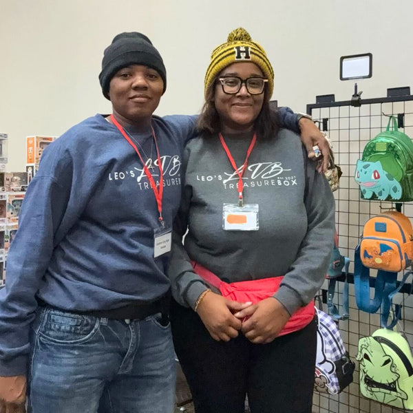 Two people wearing matching sweatshirts with a store display of backpacks in the background.